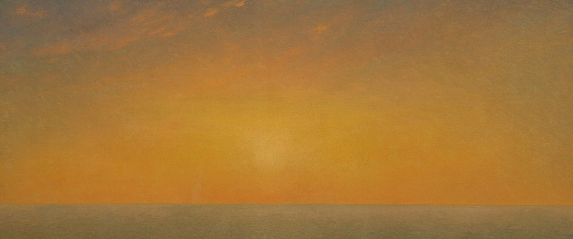 A low sun over a calm sea under a warm orange sky.