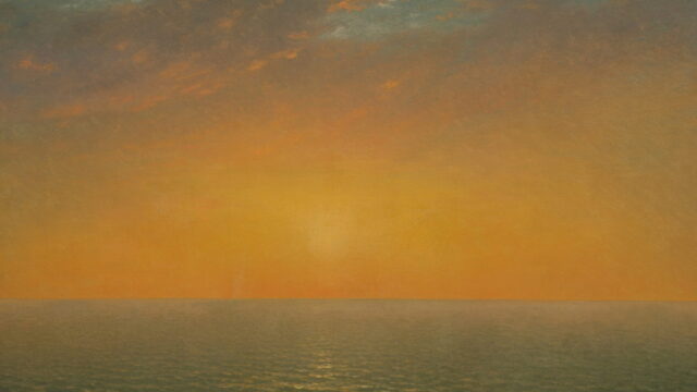 A low sun over a calm sea under a warm orange sky.