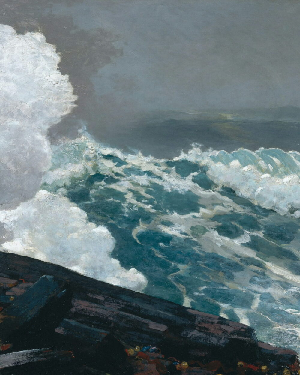 A wave bursts white over a black rock ledge under a gray sky.