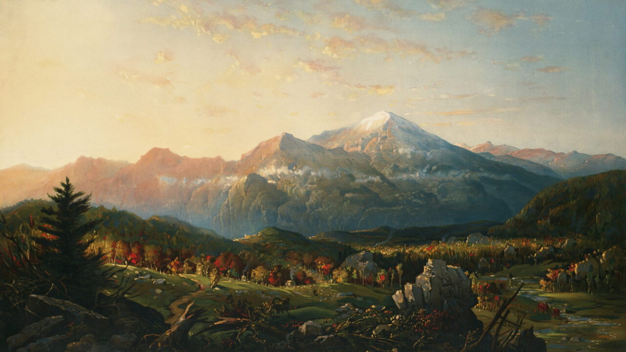 Morning light reaches a snowy peak above an autumn valley.