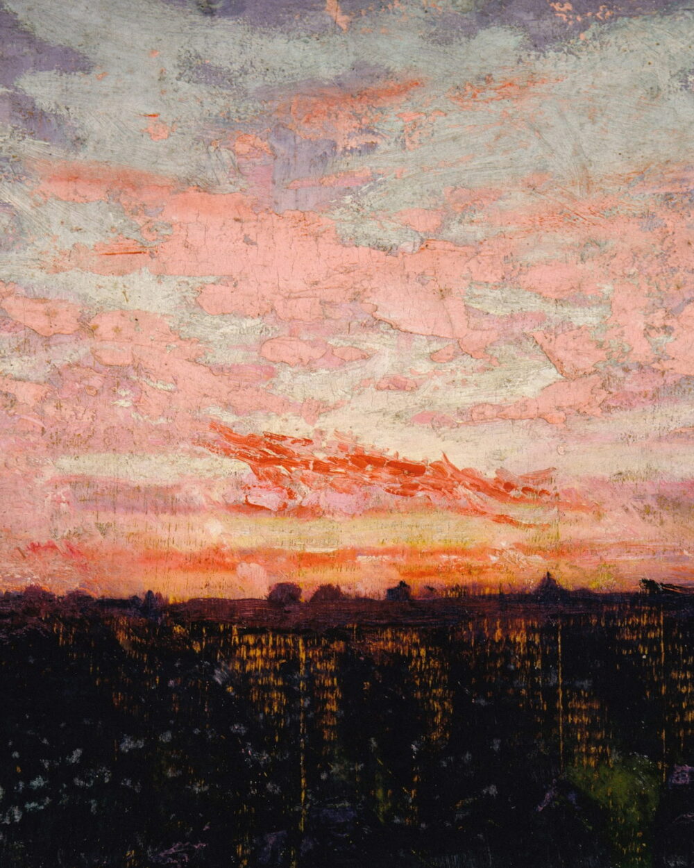 Pink and red clouds over a dark strip of land at dusk.