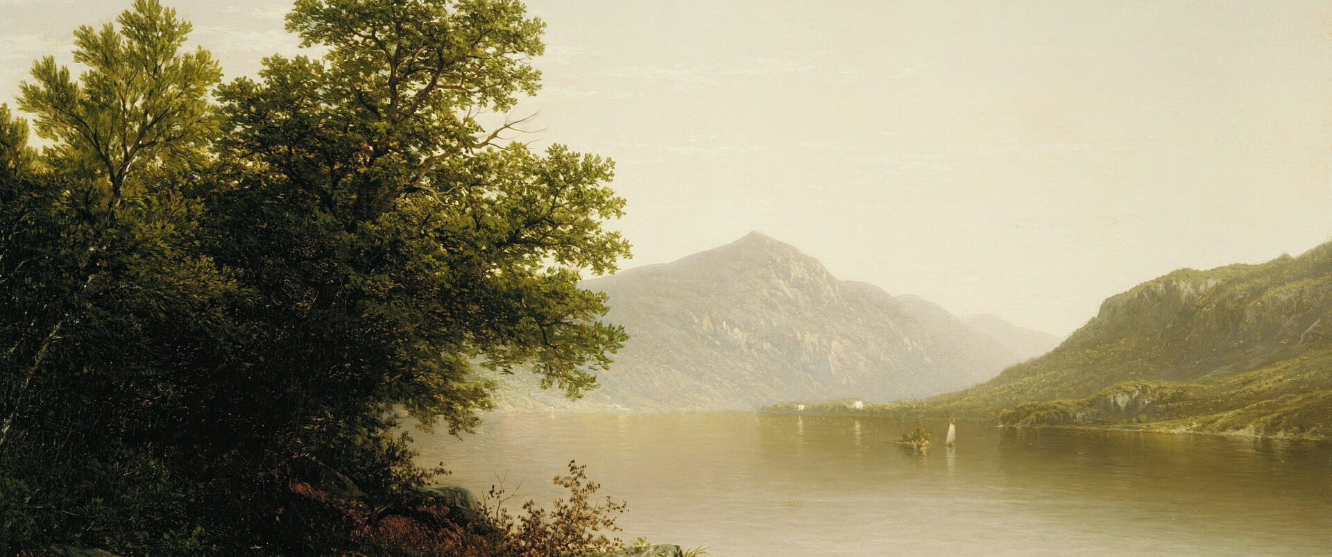 A quiet lake reflects far mountains, with one small sail on the water.