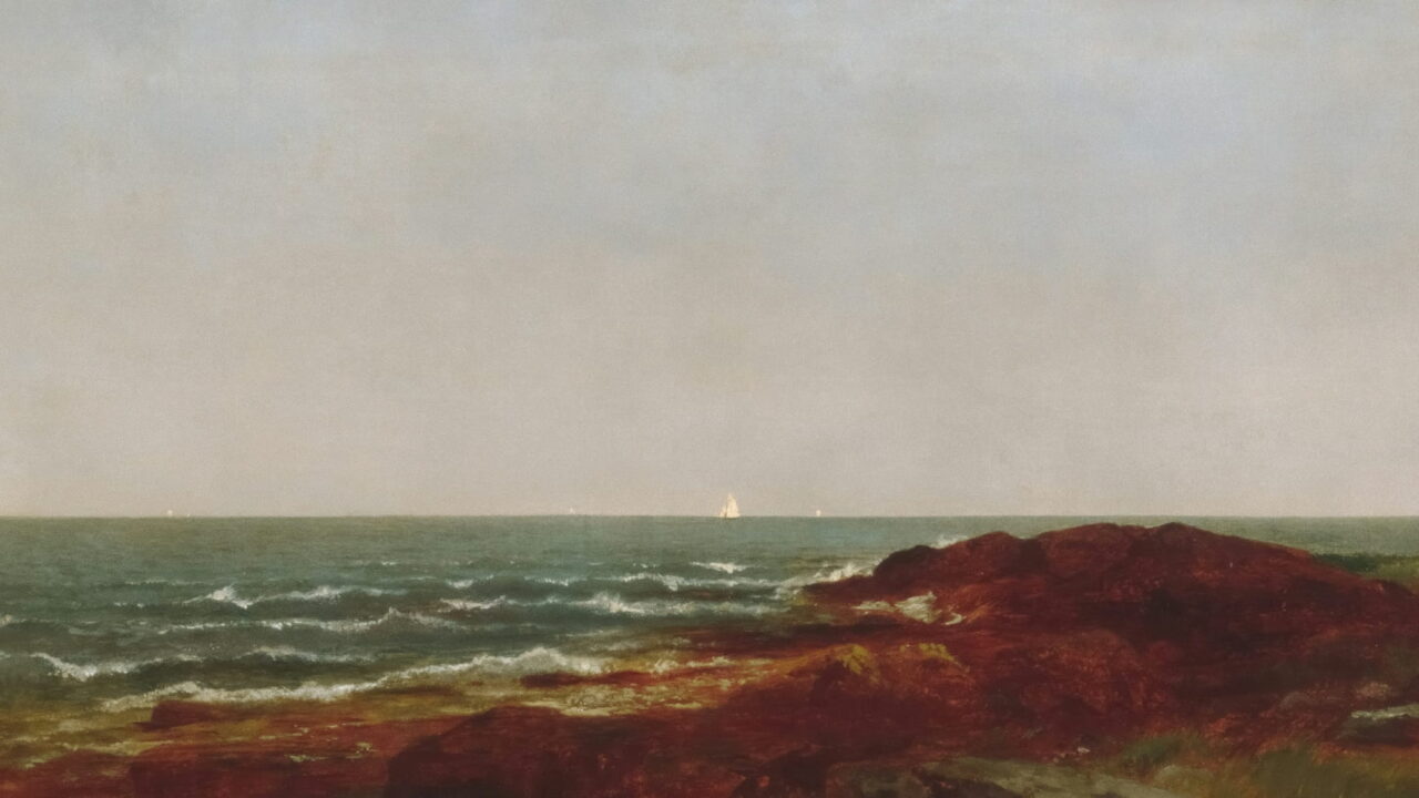 A far white sail on a gray sea above a band of dark red rocks.