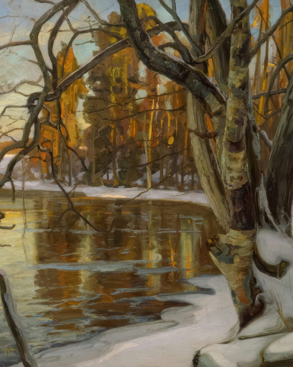 A calm winter river with snow on the bank and bare trees in low sun.