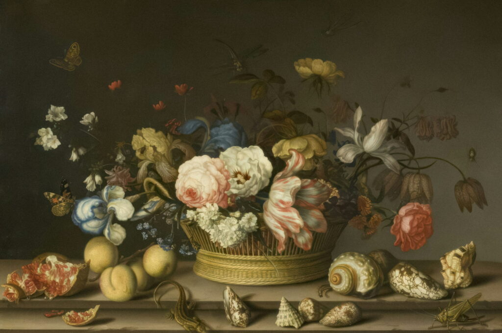 A basket of roses and tulips on a ledge with seashells laid out in front.