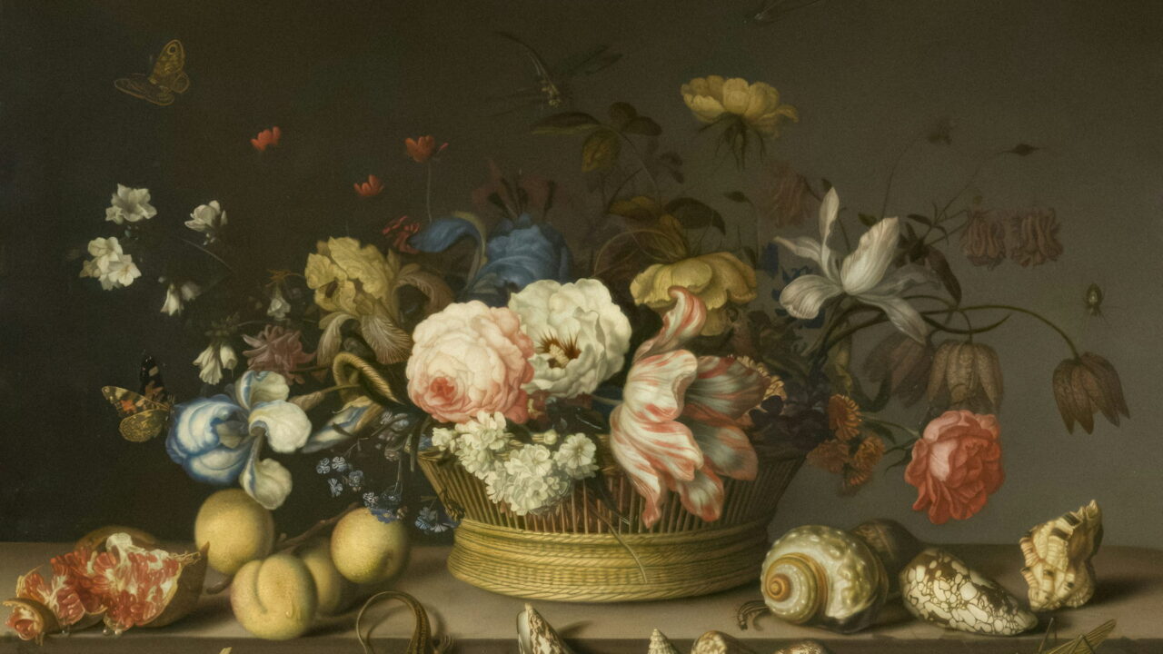 A basket of roses and tulips on a ledge with seashells laid out in front.