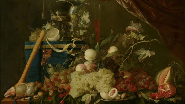 Grapes, peaches, and a silver pitcher on a table under a dark red curtain.