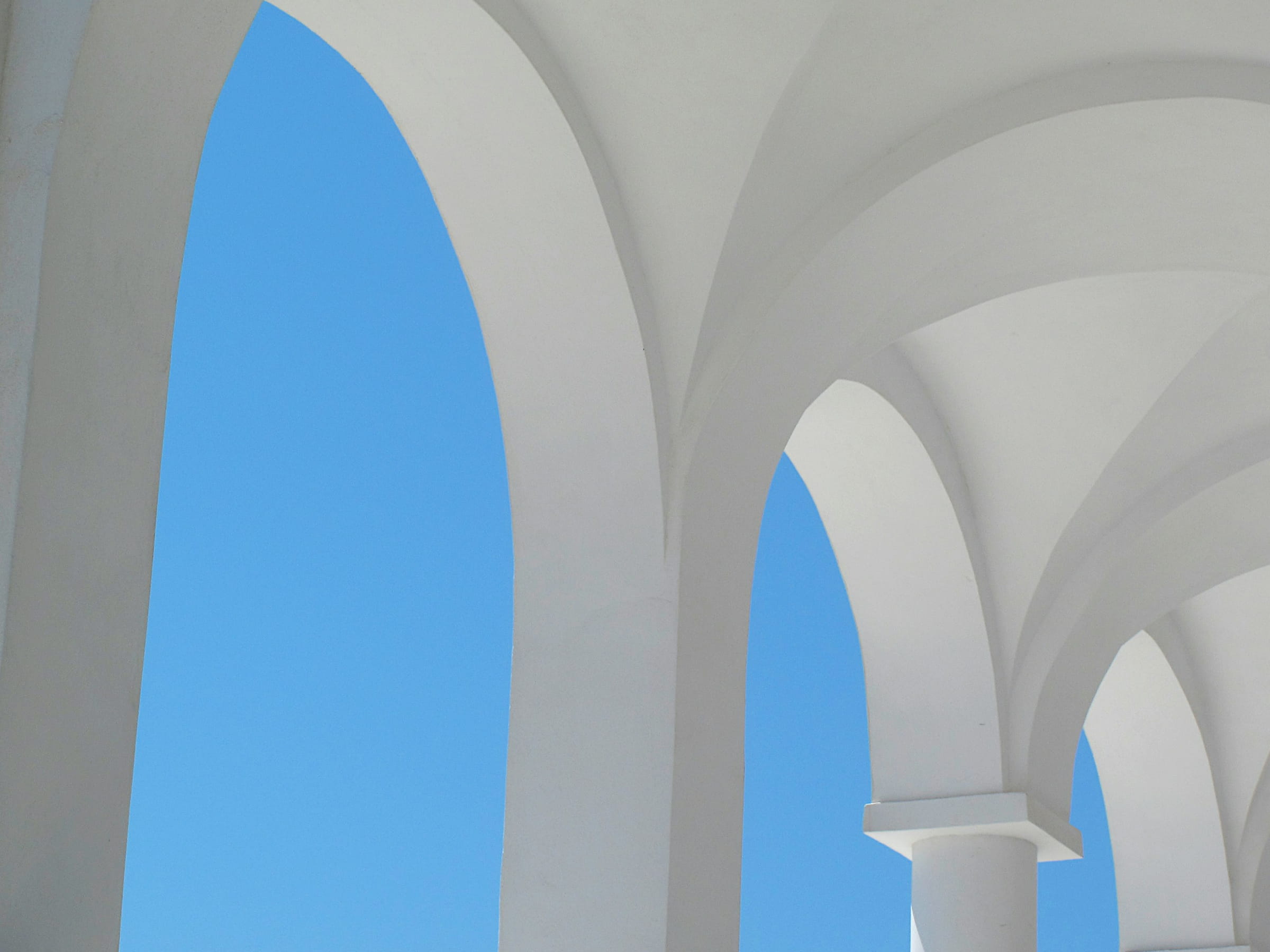 White vaulted arches open to a bright blue sky.