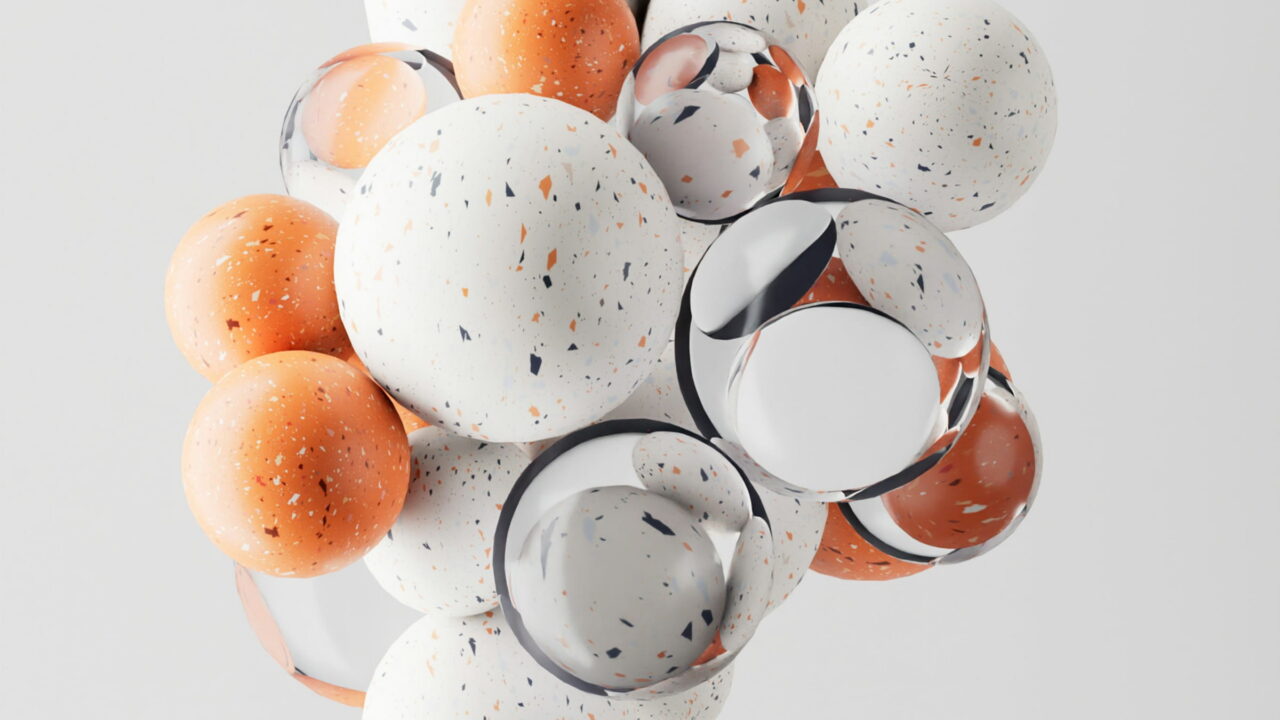 A cluster of speckled white, orange, and glass spheres on white.