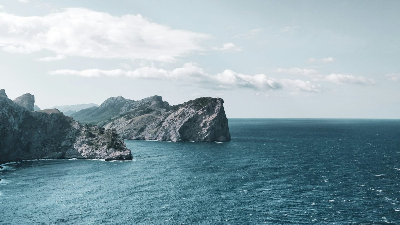Rocky headlands over a deep blue sea under white clouds.