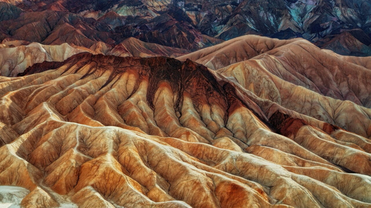 Folded badland hills in bands of orange, cream, and brown.