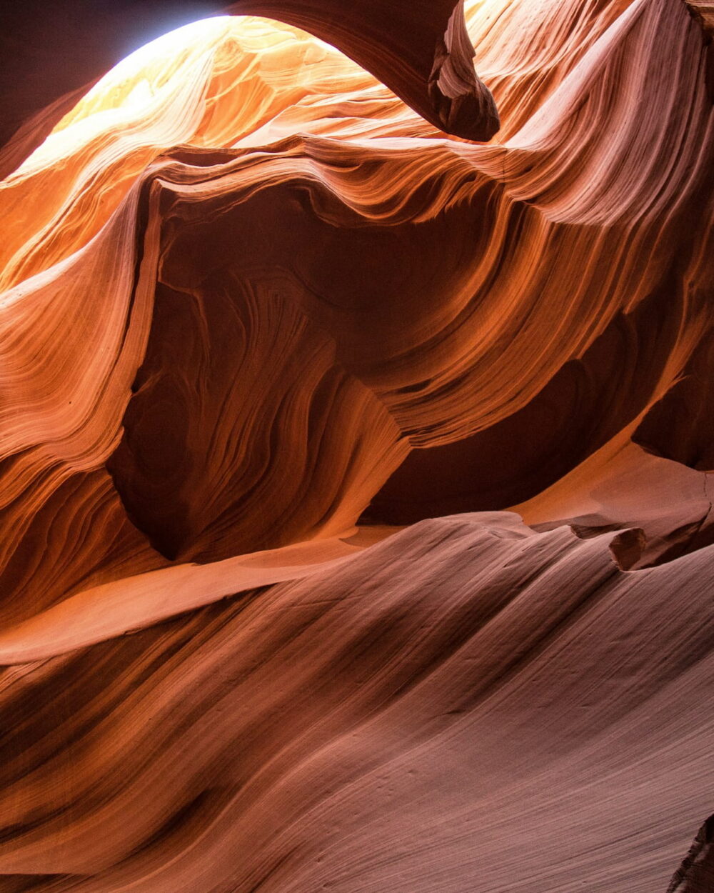 Curved orange sandstone walls glowing inside a narrow slot canyon.
