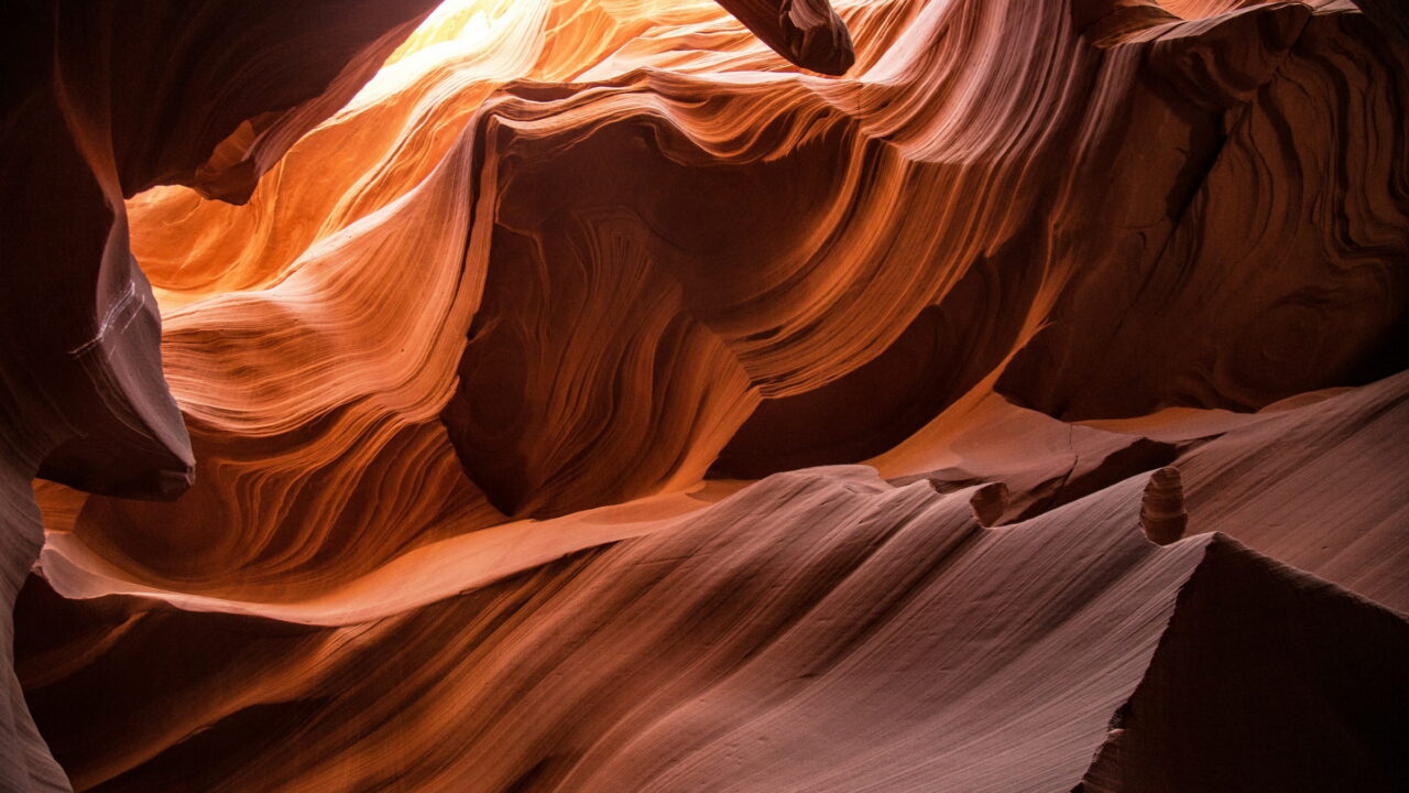 Curved orange sandstone walls glowing inside a narrow slot canyon.