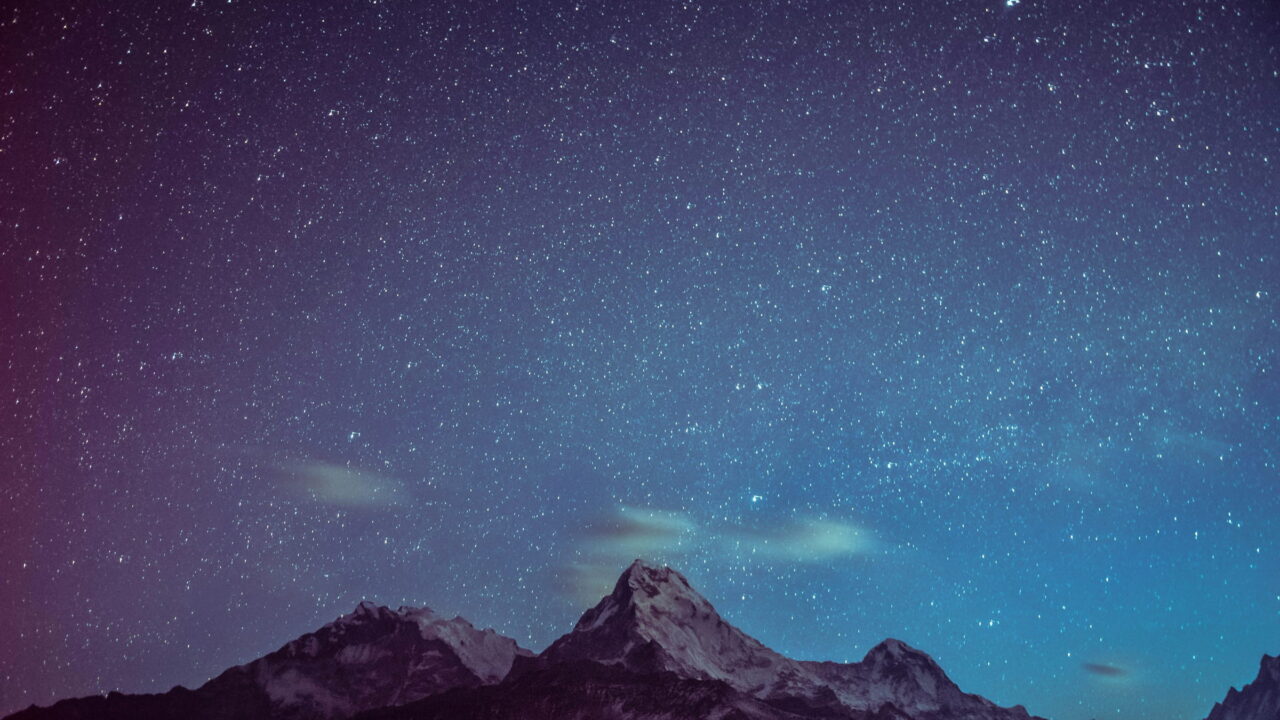 Icy peaks under a violet, starry sky with thin green clouds.